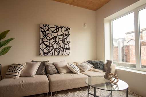 A living room with a couch, a table, and a painting on the wall.