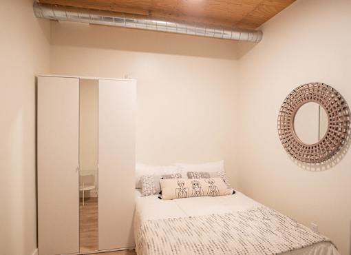 A bedroom with a bed, a mirror, and a wardrobe.