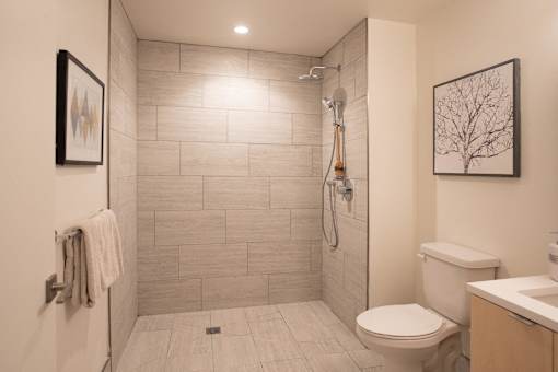 A bathroom with a toilet, sink, and tiled shower.