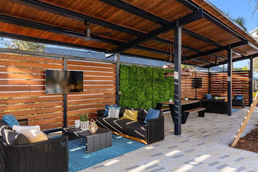 A patio with a wooden ceiling and a green wall.
