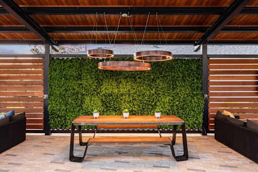 A wooden table with two cups on it in front of a green wall.