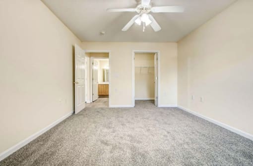 A spacious room with a ceiling fan and carpeted floor.