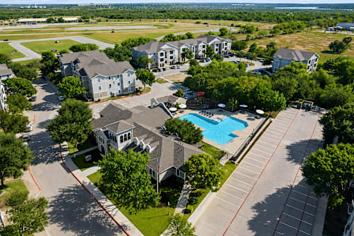 A bird's eye view of a residential area with houses, a swimming pool, and a parking lot.