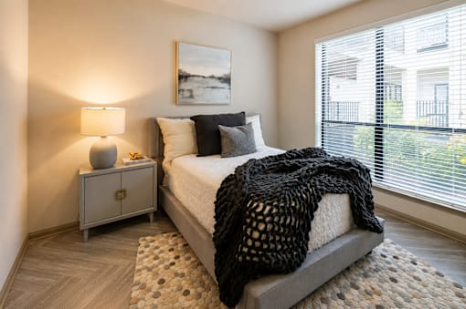 A bedroom with a bed, nightstand, and window.