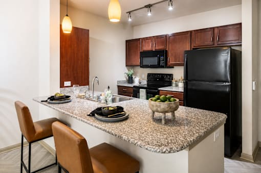 A kitchen with a granite countertop and a black refrigerator.