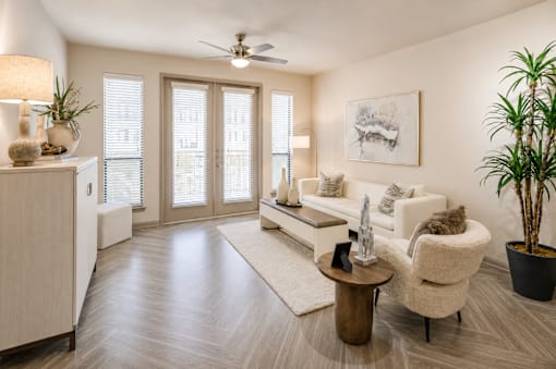 A living room with a white sofa, a wooden coffee table, and a potted plant.