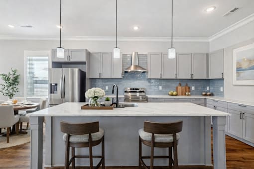 A modern kitchen with a large island and bar stools.