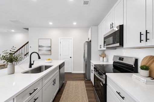 A modern kitchen with white cabinets and black appliances.