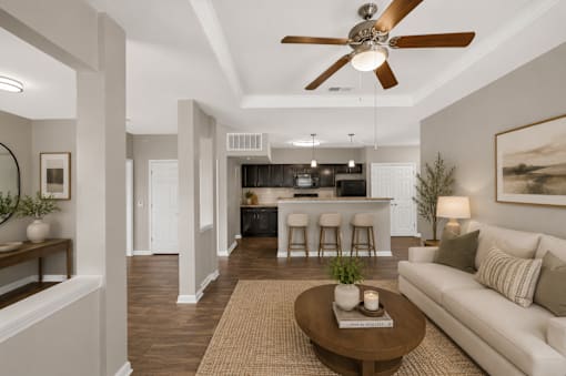 A living room with a white couch, a brown coffee table, and a ceiling fan.
