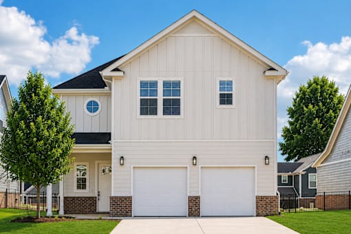 A white house with a black roof and two garages.