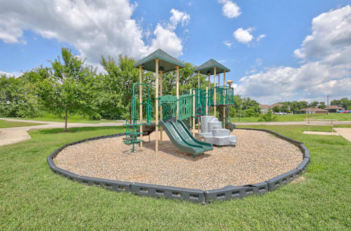 A playground with a green slide and a wooden structure.