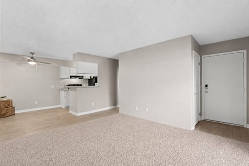 A room with a ceiling fan and a kitchenette.