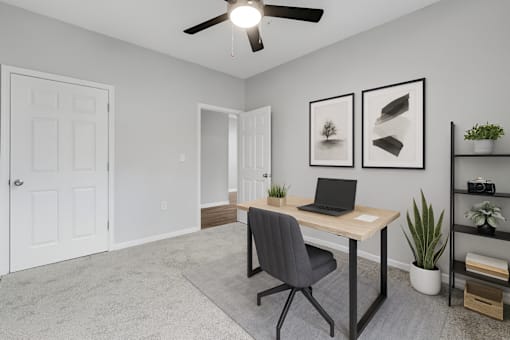 A room with a desk, chair, and a ceiling fan.