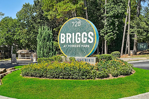 A sign for Briggs at Powers Park is surrounded by greenery.
