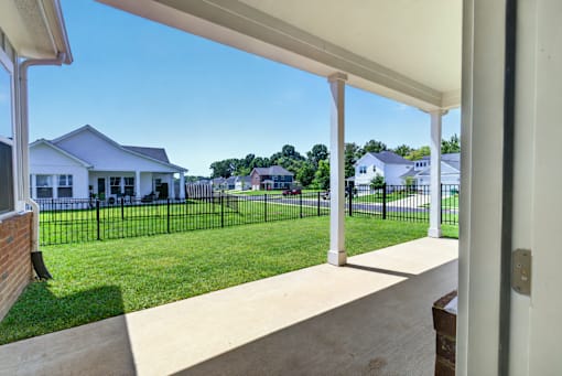 A white house with a black fence and a green lawn.