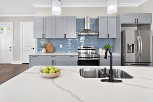 A modern kitchen with a marble countertop and stainless steel appliances.