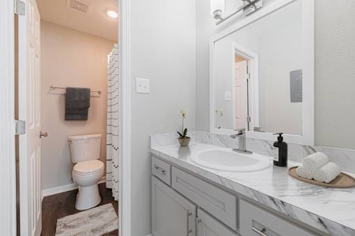 A bathroom with a toilet, sink, and mirror.