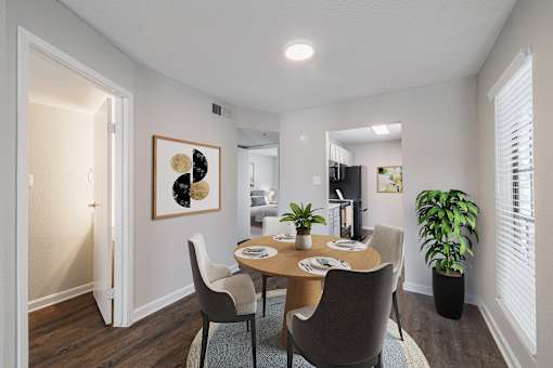 A dining room with a table set for two and a potted plant.