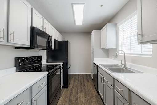 A kitchen with black appliances and white cabinets.