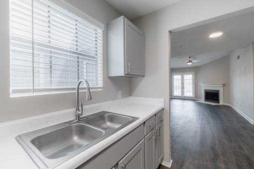 A kitchen with a sink, stove, and cabinets.