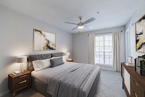 A bedroom with a large bed, a ceiling fan, and a painting on the wall.