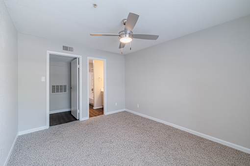 A room with a ceiling fan and carpeted floor.