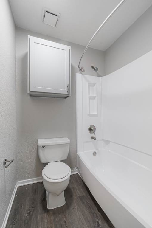 A white toilet sits next to a white bathtub in a small bathroom.