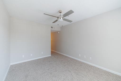 A room with a ceiling fan and carpeted floor.
