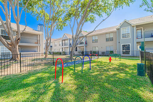 A playground with a red swing set and a blue slide in a grassy area.
