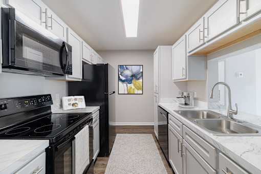 A kitchen with black appliances and white cabinets.