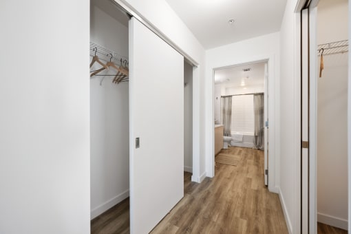 a hallway with white walls and a closet with mirrored doors