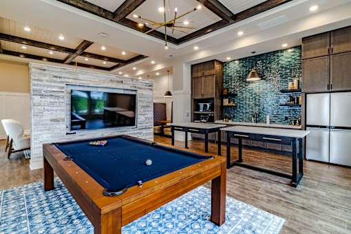 A pool table is in the middle of a room with a TV and a fireplace.