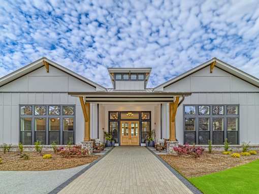 A modern house with a large front porch and a wooden walkway leading to the entrance.