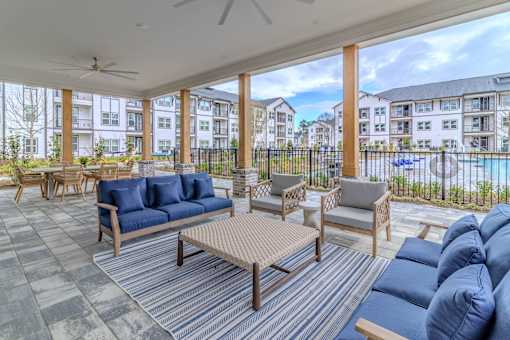 A patio with blue couches and a striped rug.