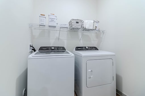 Two white front loading washing machines in a laundry room.