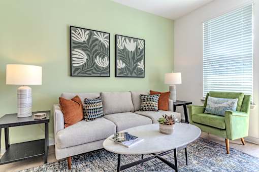 A living room with a grey couch, a green armchair, a coffee table, and two lamps.
