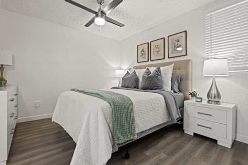 A bedroom with a bed, nightstand, and a ceiling fan.