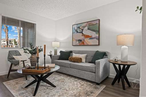A living room with a grey couch, a coffee table, and a painting on the wall.