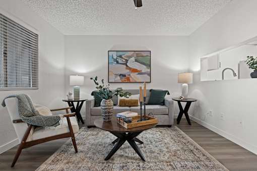 A living room with a grey couch, a wooden coffee table, and a painting on the wall.