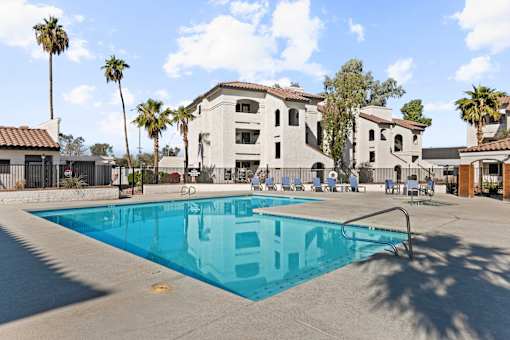 A swimming pool in front of a building with palm trees.