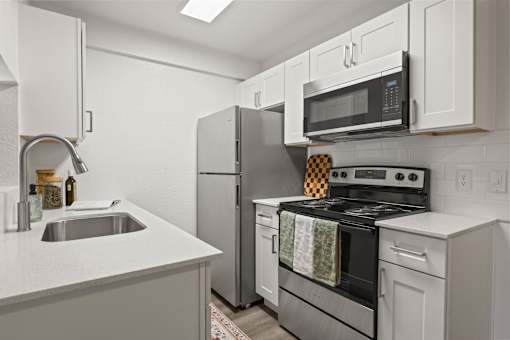 A modern kitchen with a stove, refrigerator, and microwave.
