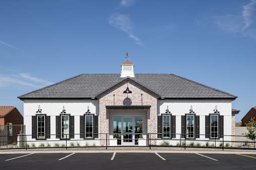 A white building with black shutters and a black roof with a white cupola.