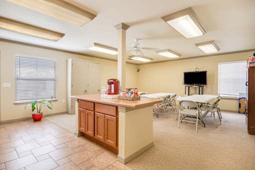 A kitchen with a table and chairs and a television.