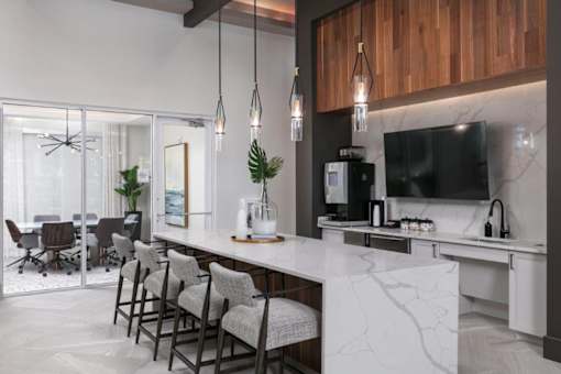 A modern kitchen with a long island and chairs.