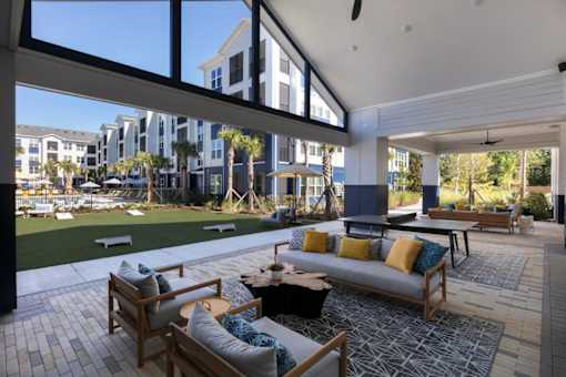 A patio with a couch and chairs overlooking a grassy area.