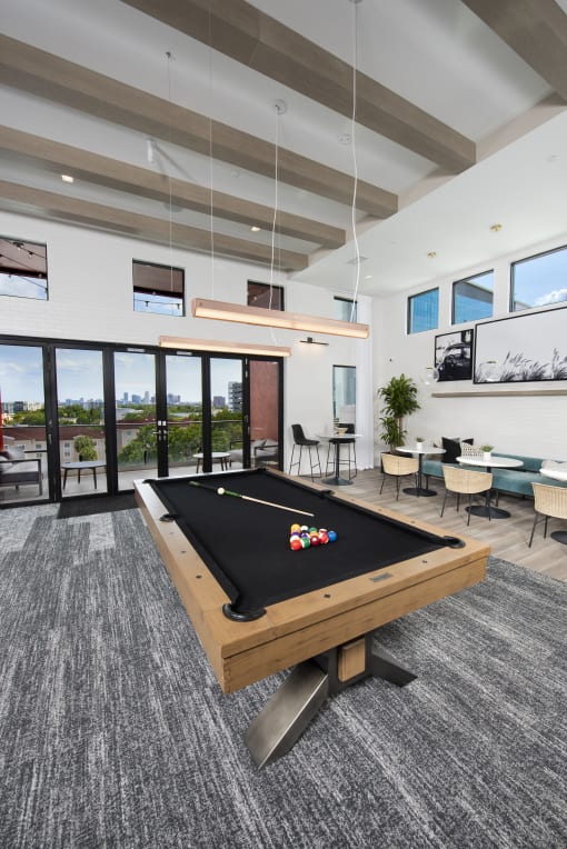 a billiards table in a clubhouse with a view of a patio and windows