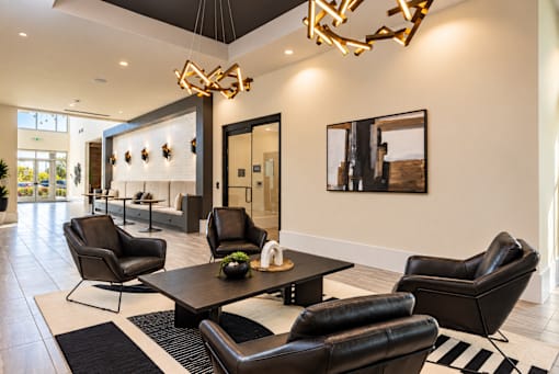 A modern living room with black leather chairs and a wooden coffee table.