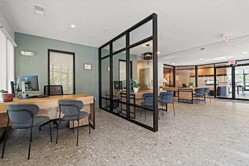 A modern office space with a glass wall and a desk with chairs.