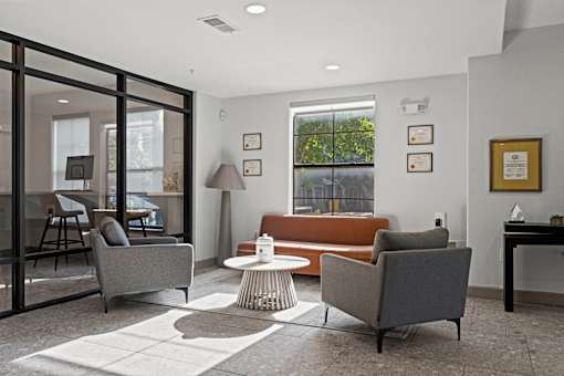 A modern living room with a grey sofa, a brown sofa, a glass table, and a white coffee table.