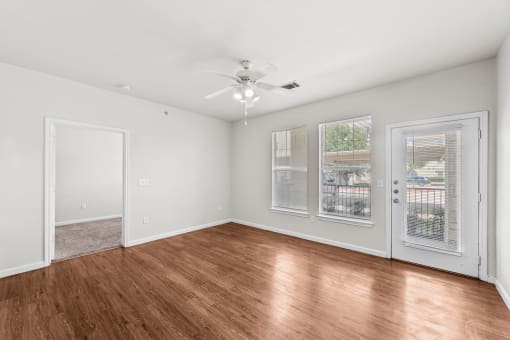 an empty living room with wood floors and a ceiling fan